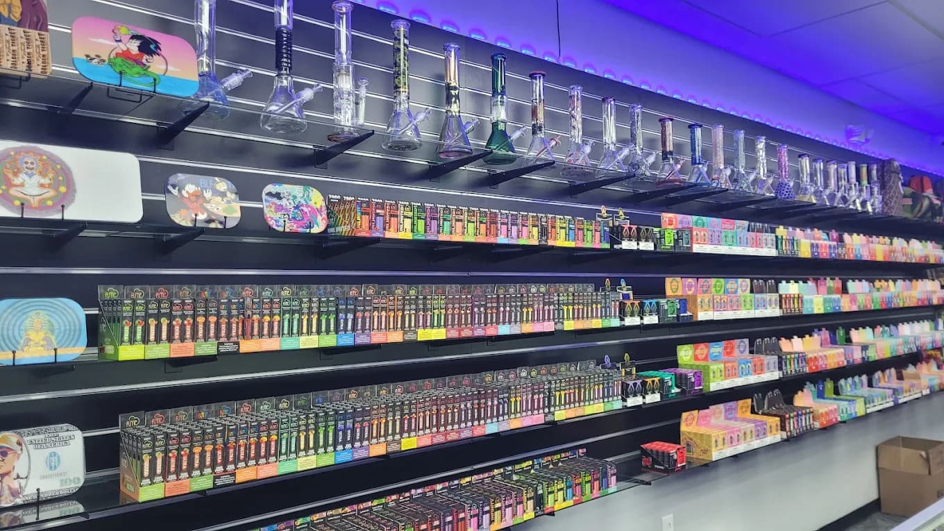 The stocked shelf wall inside the shop, rows of product lit above the glass counters.